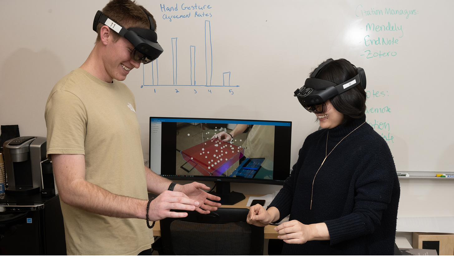 A lab member demonstrating an augmented reality headset interaction.